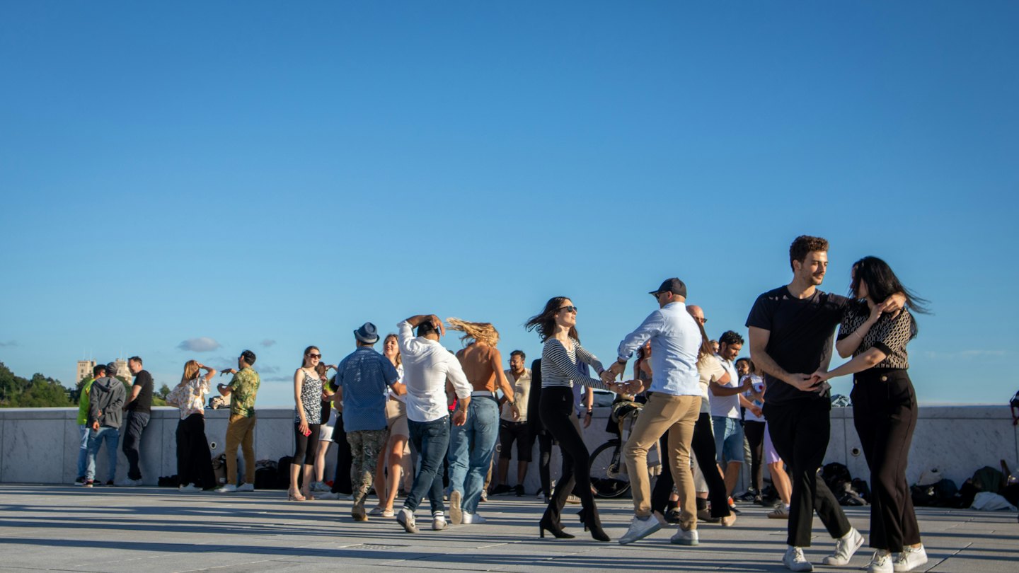 Des gens dansent ensemble sur une place pavée extérieure.